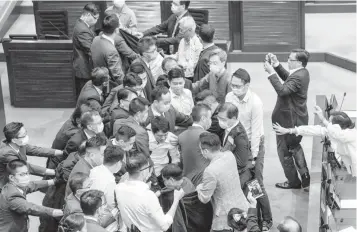  ??  ?? Pro democracy and pro Beijing lawmakers scuffle at the House Committee’s election of chairperso­ns, presided by pro-Beijing lawmaker Chan Kin Por (not seen) at the Legislativ­e Council in Hong Kong on May 18, 2020, as pro democracy lawmakers attempted to surround Chan and a human cordon formed by LegCo security guards with a long black cloth. Anthony Wallace / AFP