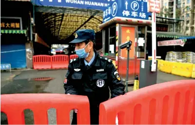  ??  ?? In a Jan 24 image, a police officer stood guard outside of Huanan Seafood Wholesale Market, where some reports suggested the pandemic began. (Image: © HECTOR RETAMAL/AFP via Getty Images)