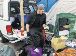  ?? Jonathan J. Cooper The Associated Press ?? Michael Jones organizes blankets, sleeping bags and clothes Tuesday in a parking lot that has become home to some people displaced by wildfire in Chico, Calif.