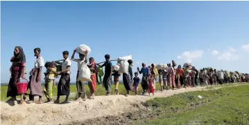  ?? (Reuters) ?? ROHINGYA REFUGEES walk toward a refugee camp after crossing the border in Anjuman Para near Cox’s Bazar, Bangladesh, earlier this month.