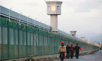  ??  ?? Workers walk by the perimeter fence of what is officially known as a Uighur ‘vocational skills education centre’ in Dabancheng, Xinjiang, China. Photograph: Thomas Peter/Reuters