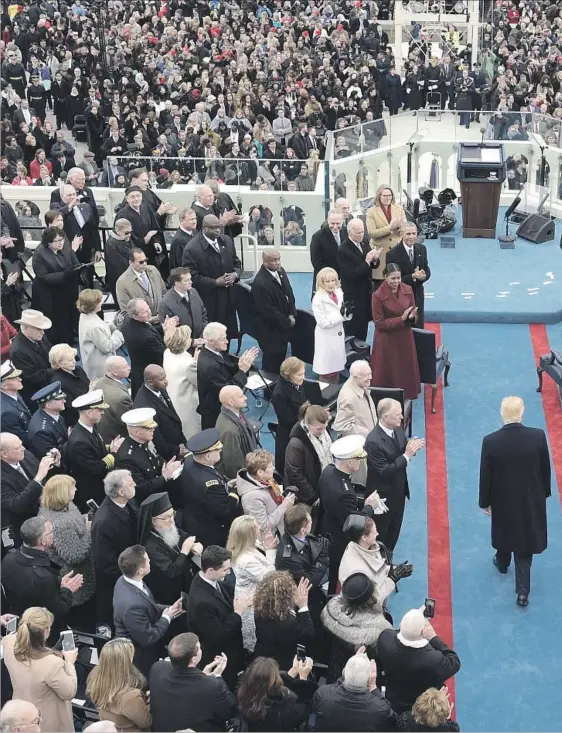  ??  ?? MOMENTS BEFORE the official transfer of the presidency, Donald Trump walks down the aisle at his inaugural ceremony. Among the crowd on the left are Presidents Obama, George W. Bush, Clinton and Carter, as well as defeated Democratic candidate Hillary...