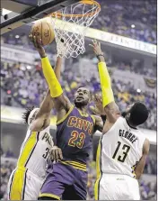  ?? DARRON CUMMINGS / AP ?? LeBron James splits Paul George (13) and Myles Turner on the drive in Cleveland’s 106-102 win over Indianapol­is to sweep the first-round playoff series.