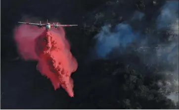  ?? PHOTOS BY CHRISTIAN MONTERROSA — ASSOCIATED PRESS ?? A plane drops fire retardant to prevent the Getty Fire from spreading further Monday in Los Angeles.