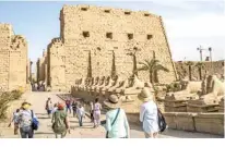  ??  ?? In this file photo tourists take the avenue of the ram-headed sphinxes, symbolizin­g the ancient Egyptian god Amun, as
they visit the Karnak Temple Complex (background) in Egypt’s southern city of Luxor.