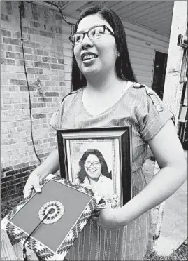  ?? ROGELIO V. SOLIS/AP ?? Kristina Taylor, 18, holds a portrait of her late mother, Sharon Taylor, and the special beaded mortarboar­d she would have worn during high school graduation ceremonies.