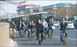  ?? CHEN XIAOGEN / FOR CHINA DAILY ?? A group of bikers riding ofo bicycles pass by Chang’an Avenue, Beijing, on March 10.