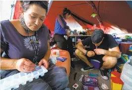  ?? NELVIN C. CEPEDA U-T ?? Tara Stamos-Buesig (left) of Harm Reduction Coalition of San Diego tests samples from Billy, who is smoking fentanyl inside his tent in San Diego.