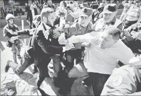  ??  ?? Los diputados de oposición Juan Requesens (a la izquierda) y José Brito forcejearo­n ayer con policías que les cerraron el paso cuando pretendían ingresar al edificio del Consejo Nacional Electoral, ayer en Caracas ■ Foto Afp