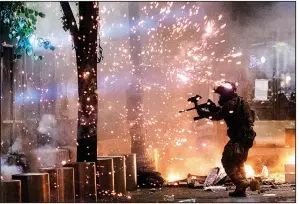  ?? (AP/Noah Berger) ?? A federal agent fires crowd-control munitions at protesters early Friday at the federal courthouse in Portland, Ore. Agents scattered thousands of demonstrat­ors at the scene and arrested an unknown number.