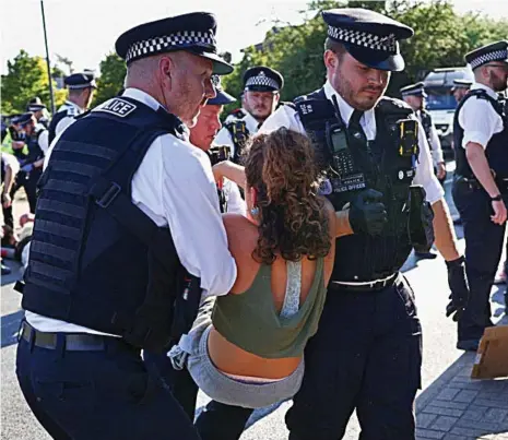  ?? ?? On its way: The coach carrying asylum seekers leaves the immigratio­n removal centre, top left, despite a protest, bottom left. Police remove one activist, left.