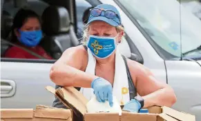  ??  ?? Good Samaritan: Volunteer Karen Cooperstei­n distributi­ng chilled milk for the public during a drive-through food pantry distributi­on by Catholic Charities in Dallas. — AP