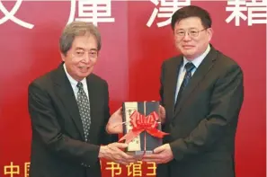  ?? CHEN XI / FOR CHINA DAILY ?? Former Japanese prime minister Morihiro Hosokawa (left) gives copies of Qunshu Zhiyao as part of a donation of more than 4,000 ancient books to Han Yongjin, director of the National Library of China in Beijing on Tuesday.