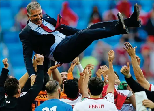  ?? GETTY IMAGES ?? Party time: Iran’s players give jubilant manager Carlos Queiroz the bumps after their last-gasp victory over Morocco