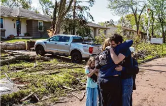  ?? Des Moines Register via Associated Press ?? Neighbors embrace Penny Thomsen on Saturday outside her home in Pleasant Hill, Iowa, one of multiple cities hit as tornadoes ripped across Iowa and Nebraska on Friday evening.