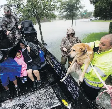  ?? BRETT COOMER/HOUSTON CHRONICLE VIA THE ASSOCIATED PRESS ?? Richard Velasco lifts his dog into an airboat to join his family during an evacuation in Fort Bend County, Tex., on Monday amid continuing heavy rains and rising flood waters of Tropical Storm Harvey.