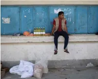  ?? (Ibraheem Abu Mustafa/Reuters) ?? A PALESTINIA­N sits next to food supplies yesterday at an aid distributi­on center run by UNRWA in Khan Yunis.