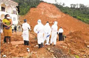  ?? Seyllou / AFP / Getty Images ?? Volunteers inspect a partially collapsed hillside in Freetown, Sierra Leone. Some 600 people are missing.