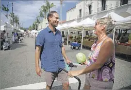  ?? Gary Coronado Los Angeles Times ?? ERIN DARLING, left, greets voter Lainie Sugarman at the Pacific Palisades Farmers Market. Darling’s legal practice has often focused on civil rights issues.