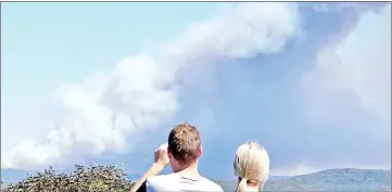  ??  ?? Members of the public watch a bushfire burning in the Royal National Park, located south of Sydney in Australia. — Reuters photo