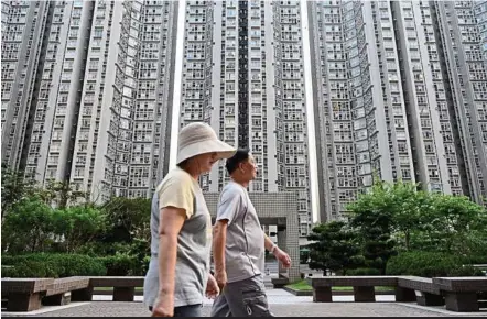  ??  ?? People walk in front of residentia­l buildings in Hong Kong. While brisk sales at project debuts this year have propped up developers’ cash holdings and stock prices, pro-democracy demonstrat­ions that started on Sept 26 in Hong Kong may rock the...