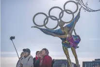  ?? MARK SCHIEFELBE­IN/ASSOCIATED PRESS ?? Visitors pose for a selfie Thursday with a statue containing the Olympic rings at a park near the headquarte­rs for the Beijing Organizing Committee for the Olympic Games in Beijing.