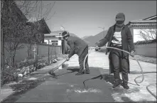  ?? PALDEN NYIMA / CHINA DAILY ?? Two villagers clean an artificial lawn in Bupal, a resettleme­nt site for impoverish­ed people in Zayul county, Tibet autonomous region.