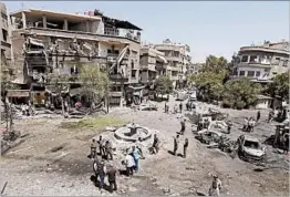  ?? LOUAI BESHARA/GETTY-AFP ?? Syrians inspect the damage Sunday after a suicide car bomb exploded in Damascus.