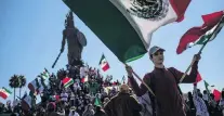  ?? PHOTO: REUTERS ?? A boy waves Mexican flags as hundreds gather around the Cuauhtemoc Monument in Tijuana yesterday to protest against migrants from Central America.