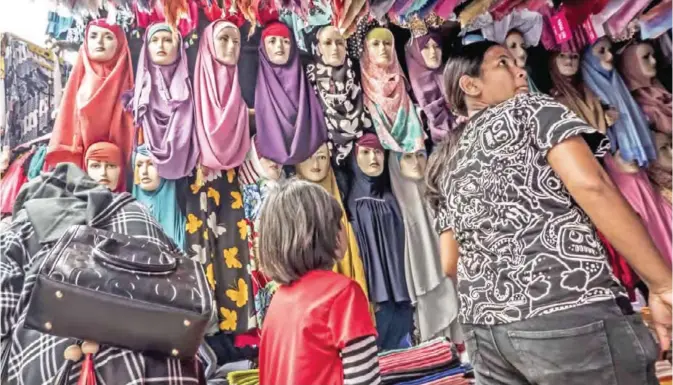  ??  ?? JAKARTA: Indonesian­s purchase clothes at a traditiona­l market. — AFP