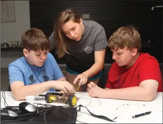  ?? The Sentinel-Record/Richard Rasmussen ?? ROBOT BUILDERS: Katie Welch, center, physics major at Hendrix College and summer intern for the National Park College Innovative Technologi­es Center, assists Adam Warner, left, and Garrett Lijewski build a robot at Robotics Camp Thursday.