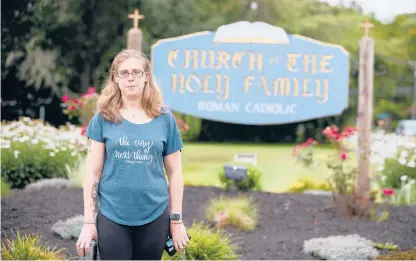  ?? SOFIE BRAND/HARTFORD COURANT ?? Lois Roy’s daughter, Rochelle Roy, stands in front of the Church of the Holy Family in Hebron. Her mother was almost killed there by a hit-and-run driver who ran her over while she was repairing cracks in the church parking lot’s pavement.