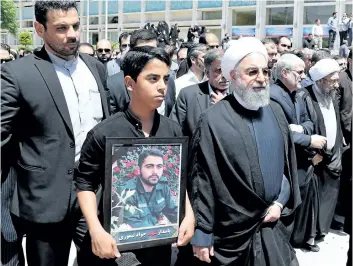  ?? GETTY IMAGES ?? Iran’s President Hassan Rouhani walks alongside the relative of a victim of twin attacks in Tehran earlier in the week during a funeral in the capital.