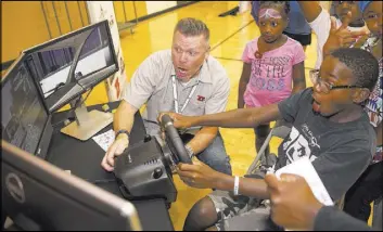  ?? Richard Brian Las Vegas Review-Journal @vegasphoto­graph ?? Jason Ealy, left, of Zero Teen Fatalities, and Zion Robinson, 8, react as Zion crashes in a driving simulator demonstrat­ion Friday during the Citywide Traffic Safety Block Party at Veterans Tribute Career &amp; Technical Academy.