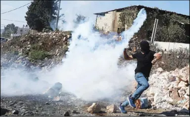  ??  ?? متظاهر فلسطيني يرمي بقارورة غاز أطلقتها قوات الأمن الإسرائيلي­ة خلال احتجاجات في كفر قدوم في الضفة الغربية أمس