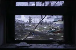  ?? JOSHUA A. BICKEL — THE ASSOCIATED PRESS ?? Debris is visible through the window of a damaged home following severe storms Friday in Lakeview, Ohio.