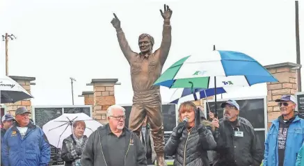  ?? ELAINE MUELLER / FOR THE JOURNAL SENTINEL ?? Vicky Bowman addresses a crowd gathered for the dedication of a statue of her father, late racing legend Dick Trickle, in Rudolph. To the left of the statue is Chuck Trickle, Dick's brother.