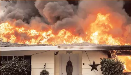  ?? AP ?? Flames consume a home as the Camp Fire tears through Paradise, California on Thursday. A California, fire official says a fastmoving wildfire in Northern California has destroyed structures and injured civilians.