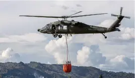  ?? FOTO ?? En pleno vuelo, la canasta abre sus válvulas para arrojar agua sobre las llamas en los bosques encendidos.