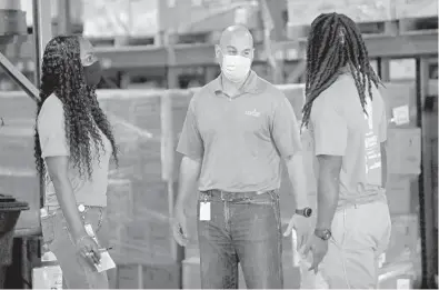  ?? SUSAN STOCKER/SOUTH FLORIDA SUN SENTINEL ?? Feeding South Florida President and CEO Paco Vélez speaks with Ketsia Eustache and T’Shaun Richardson at the group’s warehouse.