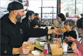  ?? PHOTOS BY SOPHIE PARK/FOR THE WASHINGTON POST ?? ABOVE: Tyler Connelly, 37, shares a bite of his fried chicken “sammie” with 2-yearold Kade Connelly at Nan’s Kitchen & Market in Southborou­gh, Mass. The restaurant and shop is in an old Wendy’s just off Interstate 495. RIGHT: Nick Hills, 26, prepares an order at Nan’s. TOP: Side dishes at Nan’s.