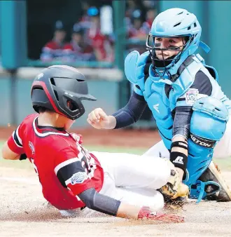  ?? TOM E. PUSKAR/THE ASSOCIATED PRESS ?? Puerto Rico catcher John Lopez tags out Canada’s Cole Balkovec Wednesday during a Puerto Rico win that eliminated Canada from the Little League World Series in Williamspo­rt, Pa.