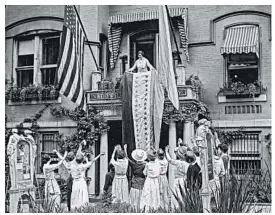  ?? THE CROWLEY COMPANY/LIBRARY OF CONGRESS ?? In this photo from Aug. 19, 1920, Alice Paul, chair of the National Woman’s Party, unfurls a banner at party headquarte­rs in Washington after ratificati­on of the 19th Amendment.