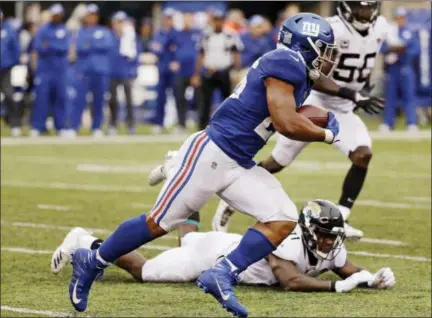  ?? SETH WENIG — ASSOCIATED PRESS ?? Giants running back Saquon Barkley rushes past Jaguars’ Yannick Ngakoue on a 68-yard touchdown run in the second half of Sunday’s game at East Rutherford, N.J.