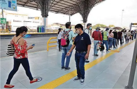  ?? CARLOS BARROS ?? kEn la estación Río Daule, en el norte, personal de biosegurid­ad indica la señalética a los usuarios para que mantengan el distanciam­iento adecuado.