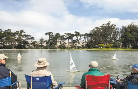  ?? Jessica Christian / The Chronicle ?? Til Mossi (left), Larry Cumeo, Bob Pearsall and Michael Fischer enjoy the weather while steering model ships in Golden Gate Park.