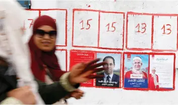  ?? (Zoubeir Souissi/Reuters) ?? WOMEN WALK past election posters of presidenti­al candidates in Tunis this week.