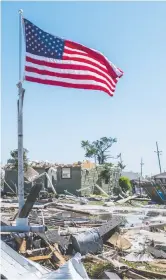  ?? BRANDON BELL / GETTY IMAGES ?? A U.S. flag flies in a field of tornado wreckage in the Arabi neighbourh­ood of New Orleans on Wednesday after two tornadoes struck the area
leaving one person dead.