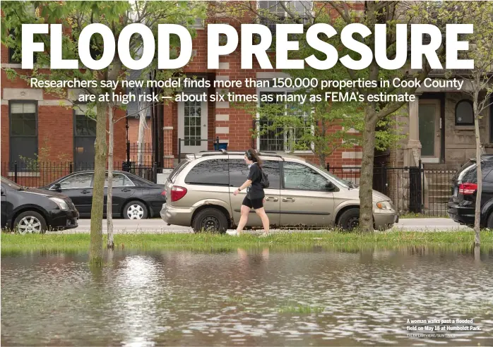  ?? TYLER LARIVIERE/SUN-TIMES ?? A woman walks past a flooded field on May 18 at Humboldt Park.