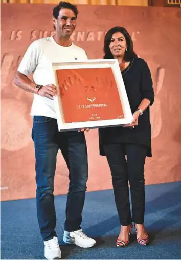  ?? AFP ?? Rafael Nadal poses with Paris’ Mayor Anne Hidalgo at the end of a press conference at the Paris city hall yesterday, a day after he won his 11th French Open title in Roland Garros.